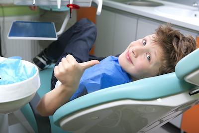 young boy giving thumbs up in dental chair