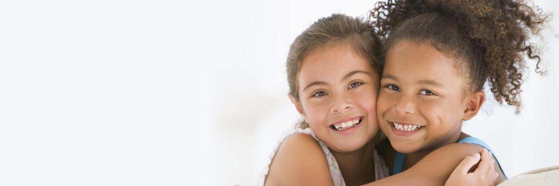 two young girls smiling while hugging