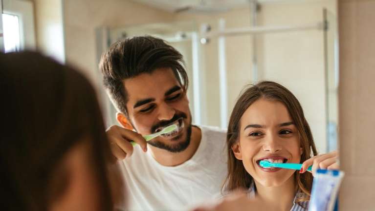 A couple brushing their teeth