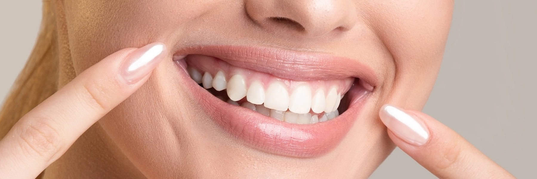 Woman displaying bright white teeth with fingers framing her confident smile